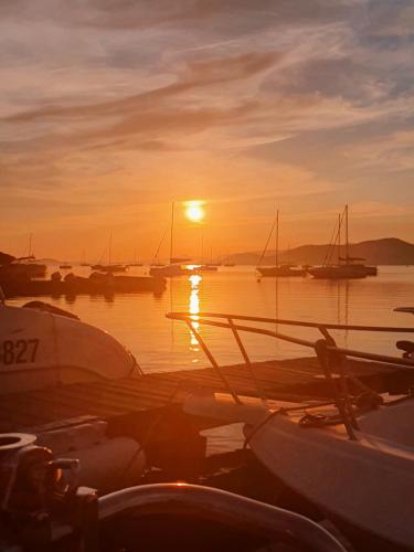 un coucher de soleil sur un port avec des bateaux dans l'eau dans l'établissement Porquerolles - Nuit insolite à bord du Défi Fou, à Porquerolles