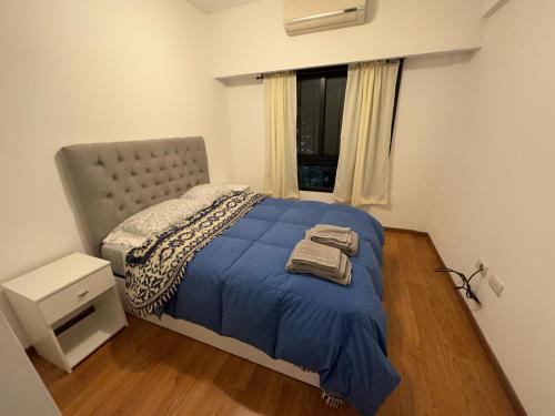 una camera da letto con un letto con una coperta blu e una finestra di Dos ambientes en Caballito a Buenos Aires