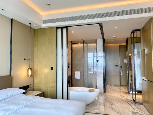 a bedroom with a bath tub and a bed at Zhangjiagang Marriott Hotel in Zhangjiagang