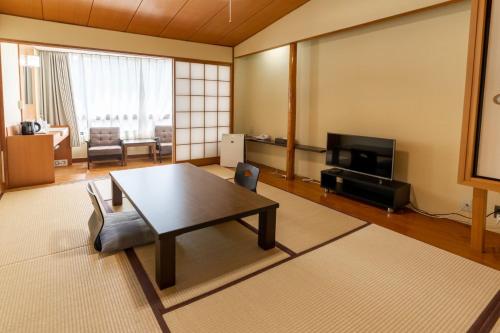 a living room with a table and a tv at Atami Onsen Hotel Yume Iroha in Atami
