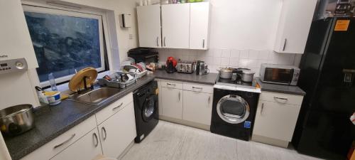 a kitchen with a sink and a washing machine at Spacious Room with Kichenet in Greasbrough