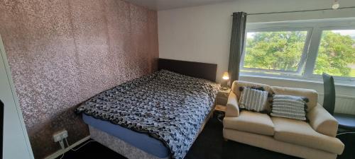 a bedroom with a bed and a couch and a window at Spacious Room with Kichenet in Greasbrough