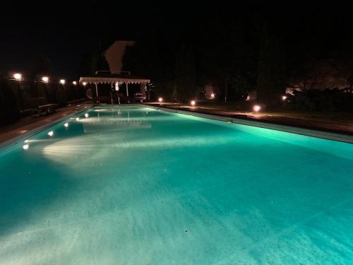 Alamedin Serenity Villa في Alamedin: مسبح كبير في الليل مع شرفة