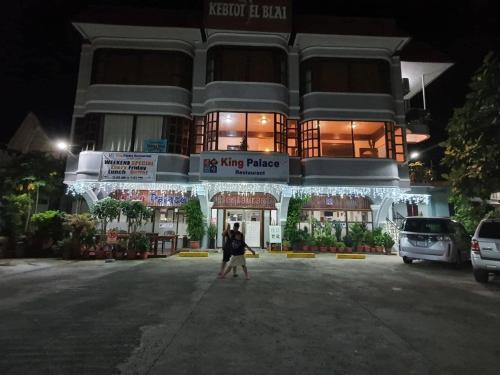 Una mujer caminando delante de un edificio por la noche en Paradise Comfort en Koror