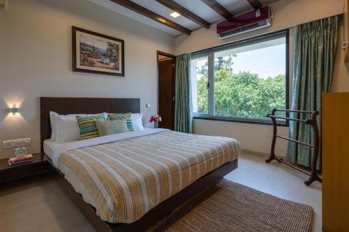 a bedroom with a bed and a large window at Emilia Villa by VEO - Part of StayVista in Mahabaleshwar