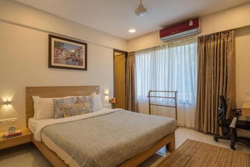 a bedroom with a bed and a window with a desk at Emilia Villa by VEO - Part of StayVista in Mahabaleshwar