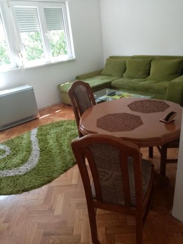 ein Wohnzimmer mit einem Tisch und einem grünen Sofa in der Unterkunft Martin in Belgrad