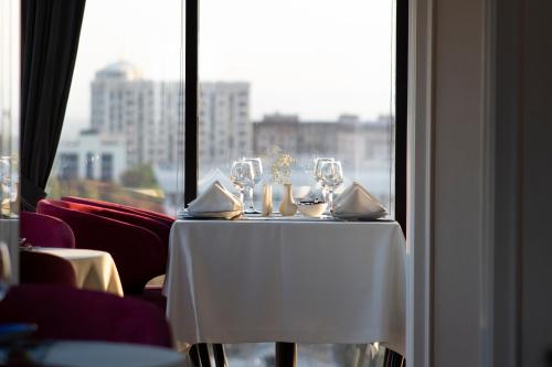 a table with wine glasses on it in front of a window at Orient Hotel Bishkek in Bishkek