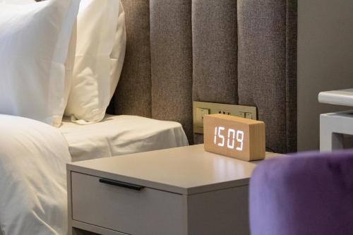 a alarm clock sitting on a table next to a bed at Orient Hotel Bishkek in Bishkek