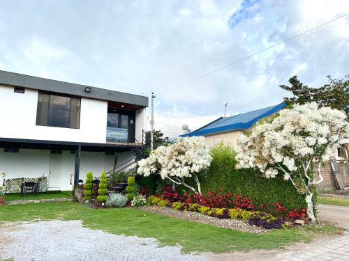 ein Haus mit weißen Blumen im Hof in der Unterkunft Hospedaje El Girasol TABABELA in Quito