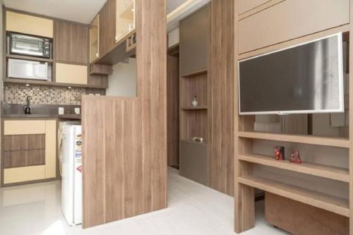 a kitchen with wooden cabinets and a flat screen tv at Belo Exclusivo AP Com Garagem na Cidade Baixa Próximo a Santa Casa, UFRGS e Centro Histórico - BnB Serviços Inteligentes Por Fioravante in Porto Alegre
