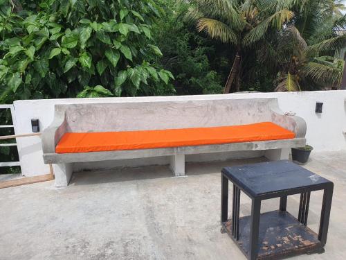 a concrete bench with an orange cushion and a stool at River Front Villa in Wadduwa