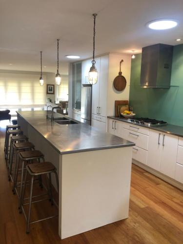 a kitchen with a large white island with bar stools at Absolute waterfront in Raglan