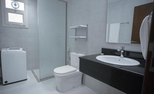a white bathroom with a sink and a toilet at Anisa Residential Complex in Salalah