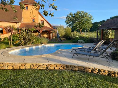 a pool with two chairs and a table in a yard at Domaine des pierres trouvées in Saint-Vincent