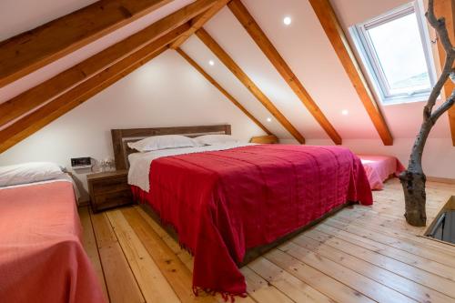 a bedroom with a red bed in a attic at Green house in Dograde