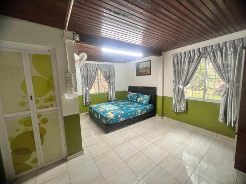 a bedroom with a bed in a room with windows at Country house Pulai Holiday Village in Gua Musang
