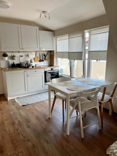 a kitchen with white cabinets and a table and chairs at Dockview atelier in Burgas