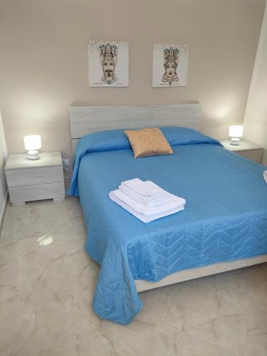 a bedroom with a blue bed with towels on it at Casa Vacanze l' angolo dei Mori in Termini Imerese