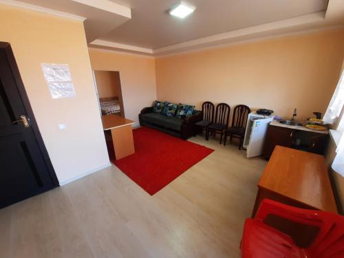 a living room with a black couch and a red rug at Salute guest house in Kaji-Say