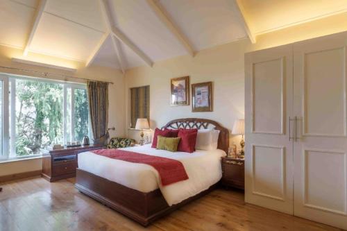 ein Schlafzimmer mit einem großen Bett und einem großen Fenster in der Unterkunft Raman Villa, Shimla, amã Stays & Trails in Shimla