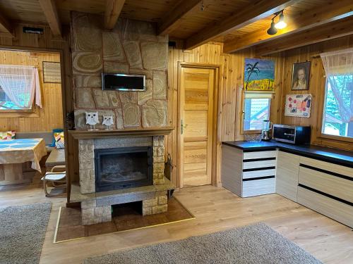 a living room with a stone fireplace in a cabin at Mazury na Śląsku - Dom Wakacyjny z basenem in Boguchwałowice