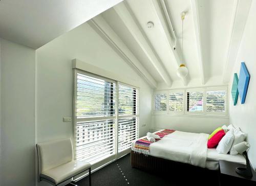 1 dormitorio con 1 cama, 1 silla y 1 ventana en Stillwell Hotel, en Charlotte Pass