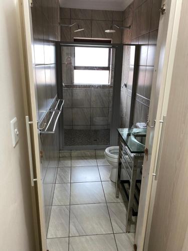 uma casa de banho com um chuveiro, um WC e um lavatório. em Flip-Flops em Jeffreys Bay