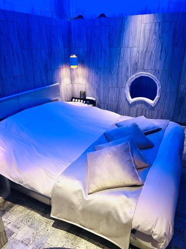 a blue bedroom with a large bed with pillows at Asokono Hotel in Kami-seya