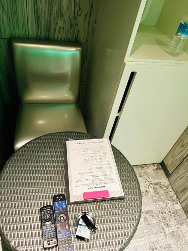 a table with three remote controls and a book at Asokono Hotel in Kami-seya