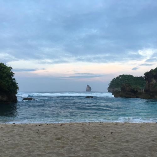 a beach with a rock in the water and the ocean at Grand Miami Hotel in Malang