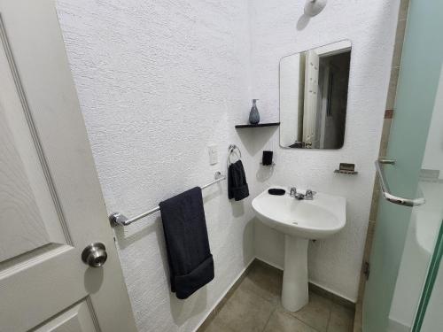 Baño blanco con lavabo y espejo en Hermosa Casa en Jardines Cancún en Cancún