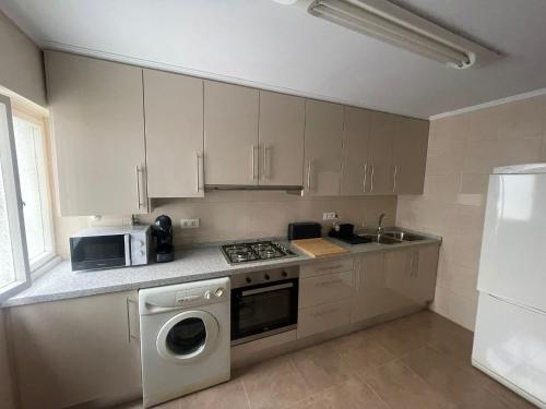 a kitchen with white cabinets and a stove and a microwave at BEGOÑA SUITE in Gijón
