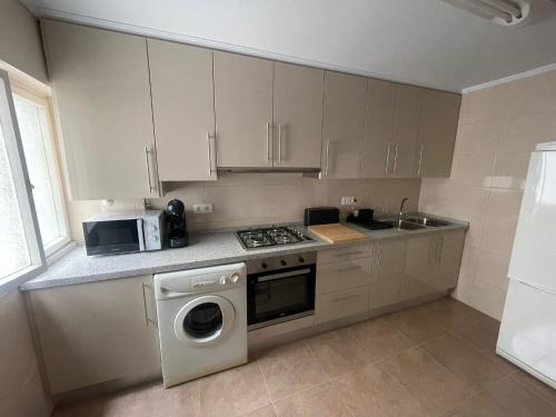 a kitchen with a washing machine and a microwave at BegoÑa Suite in Gijón