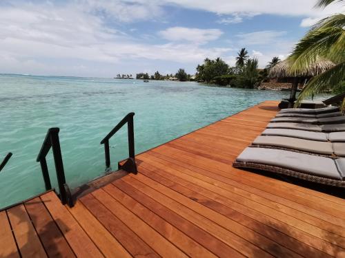 a wooden deck with lounge chairs on the water at Hôtel Fenua Mata'i'oa in Papetoai