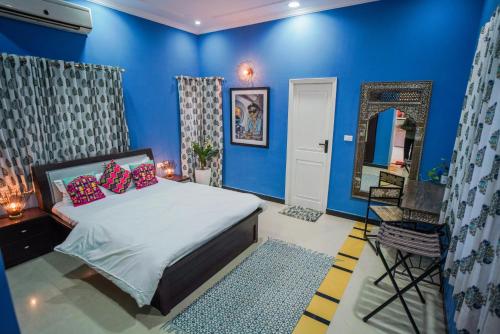 a blue bedroom with a bed and a mirror at Woodlands Cottage - Luxury stay in Jodhpur