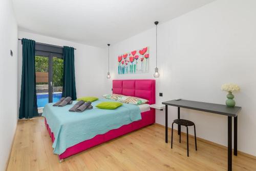 een slaapkamer met een roze bed en een bureau bij Villa Balun in Orihi - 3 bedrooms - pool - garden - sauna in Orihi