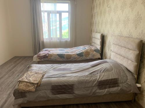 2 Einzelbetten in einem Zimmer mit Fenster in der Unterkunft Ksenya B&B in Tatev