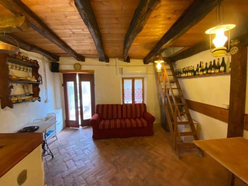 een woonkamer met een rode bank en een ladder bij Tipico rustico in pietra friulana in Budoia
