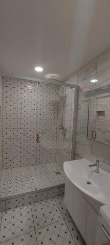 ein weißes Bad mit einer Dusche und einem Waschbecken in der Unterkunft Trumpalaikė apartamentų nuoma centre (Vytauto g.) in Šiauliai