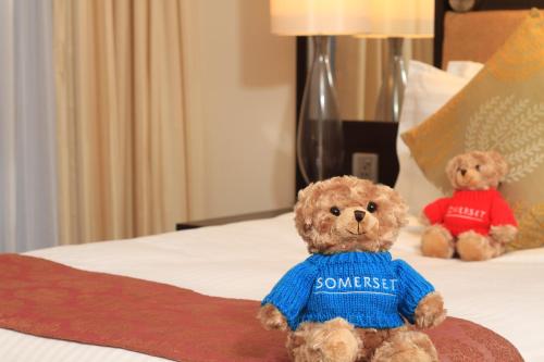 two teddy bears sitting on a bed at Somerset Greenways Chennai in Chennai