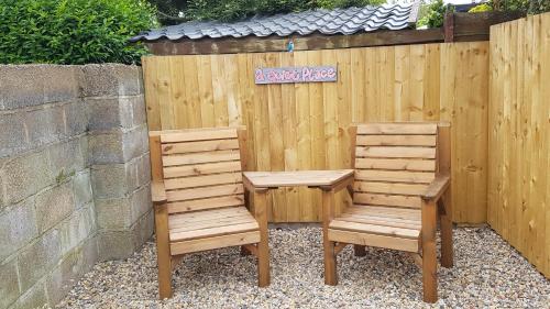 two wooden chairs sitting next to a wooden fence at Pet Friendly Beautiful Detached Cottage close to Spurn Point, Easington and Withersea in Hull