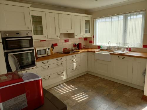 a kitchen with white cabinets and a red appliance at Pet Friendly Beautiful Detached Cottage close to Spurn Point, Easington and Withersea in Hull