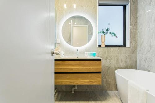 La salle de bains est pourvue d'un lavabo et d'un miroir. dans l'établissement Pristine Modern Central Home - Netflix - Heatpump, à Auckland