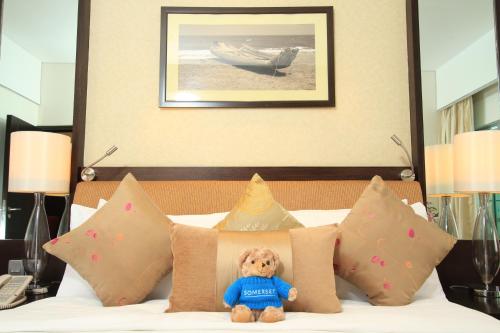 a teddy bear sitting on top of a bed with pillows at Somerset Greenways Chennai in Chennai