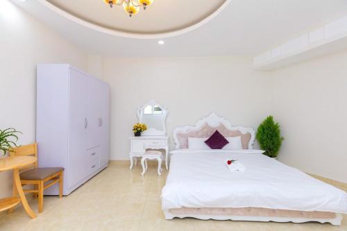 ein weißes Schlafzimmer mit einem weißen Bett und einem Schreibtisch in der Unterkunft Golden Hills A2200 in Da Lat