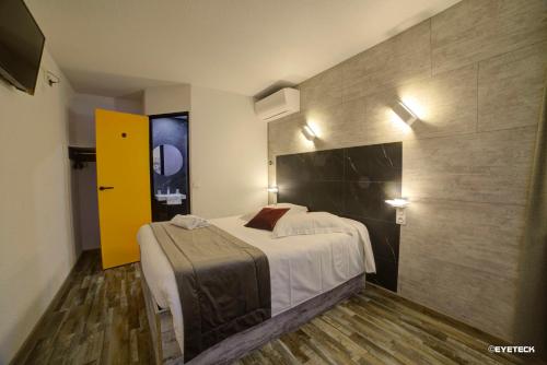 een hotelkamer met een bed en een gele deur bij Hôtel The Originals Access, Bourges Nord Saint-Doulchard in Bourges