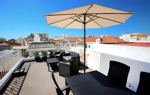 d'un balcon avec des chaises et un parasol sur le toit. dans l'établissement Isa SkyHouse Algarve, à Portimão