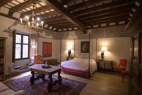 a bedroom with a bed and a table and a chandelier at Palazzo Juvalta in Teglio