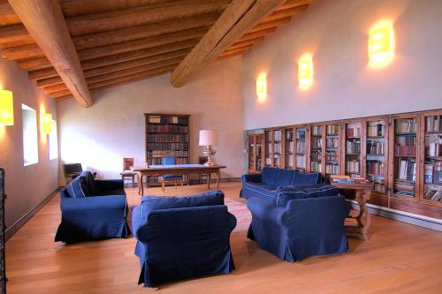 une bibliothèque avec des chaises bleues, une table et des livres dans l'établissement Palazzo Juvalta, à Teglio